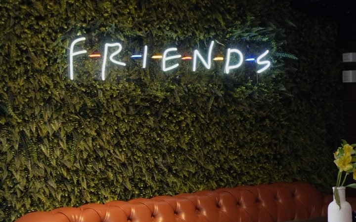 Sofá de couro e letreiro neon Friends no Cine Café
