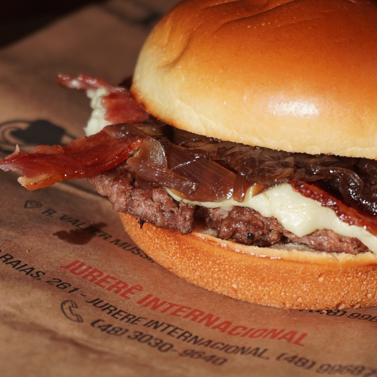 Smash burger com bacon sobre a embalagem kraft do Cine Café