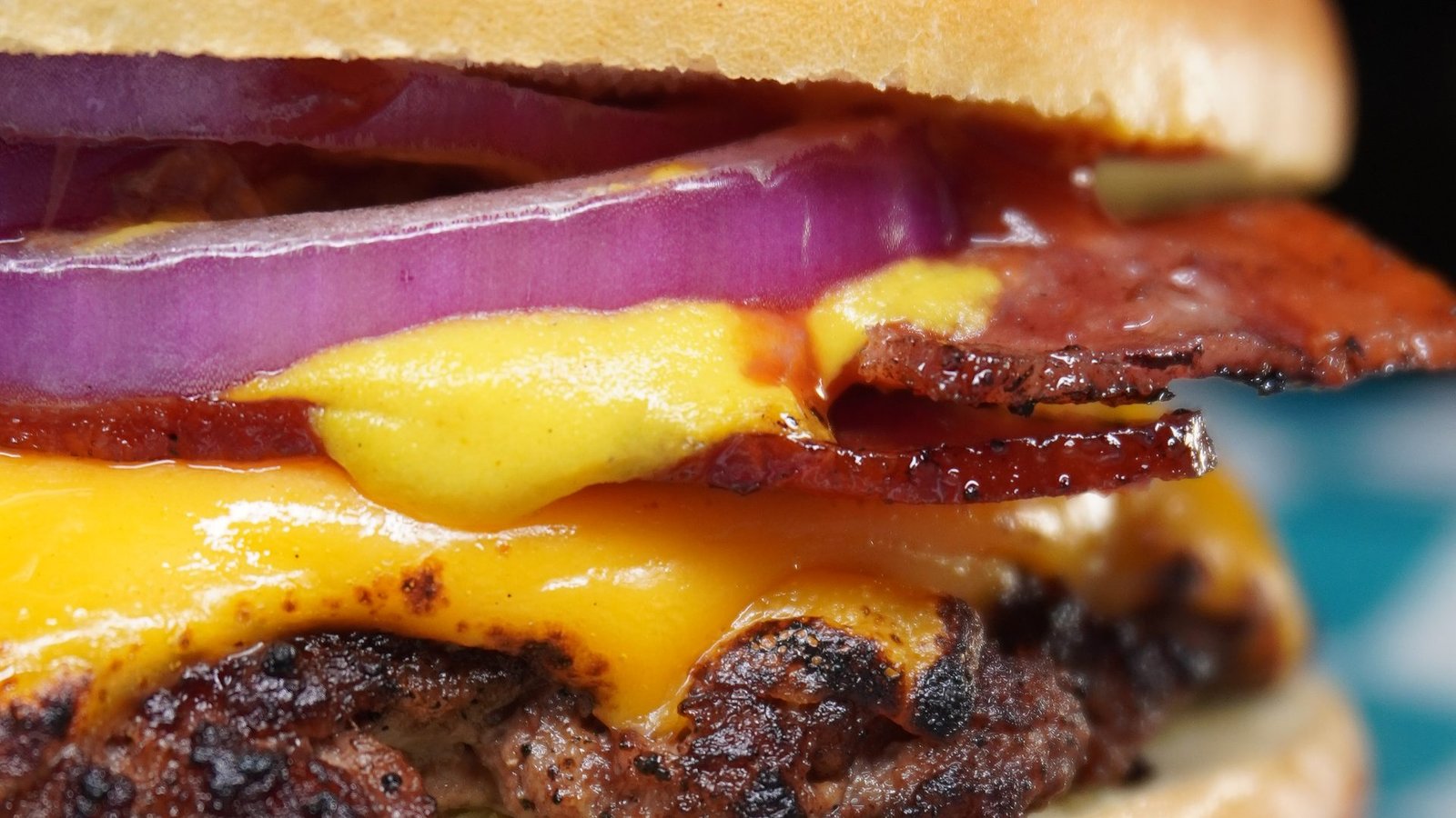 Smash burger com cheddar derretido, bacon e cebola roxa